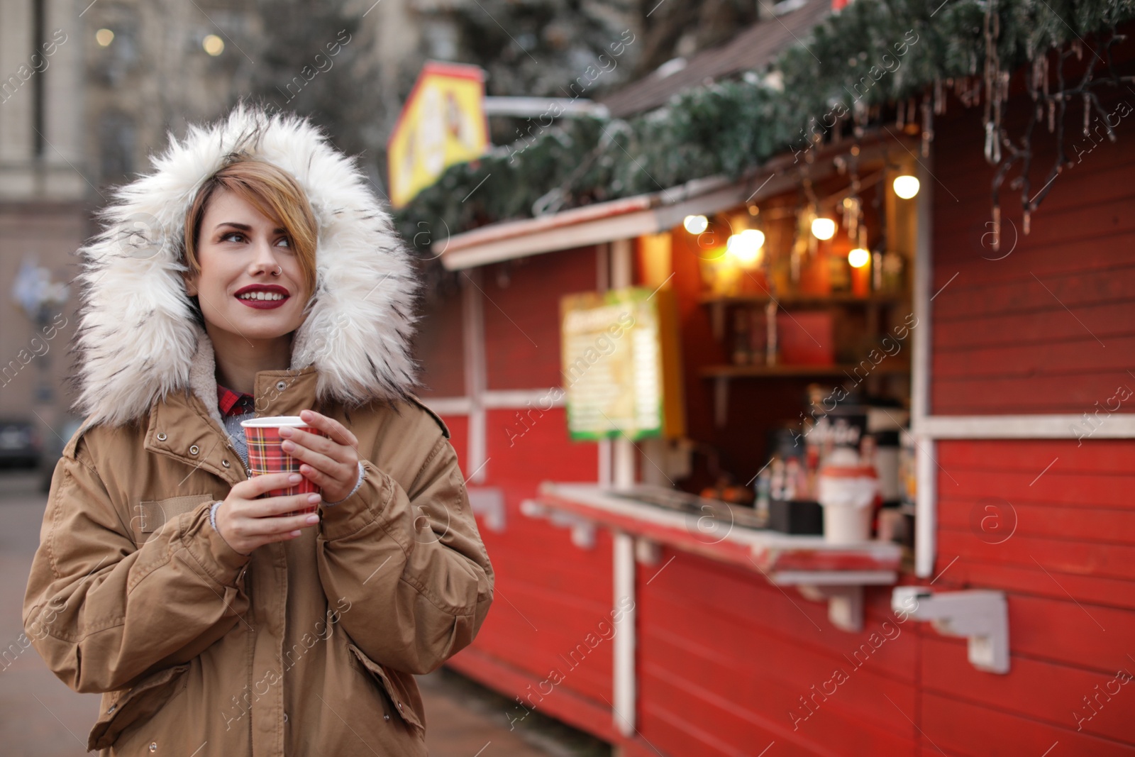 Photo of Woman with cup of mulled wine at winter fair. Space for text