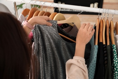 Woman choosing clothes from wardrobe rack, closeup