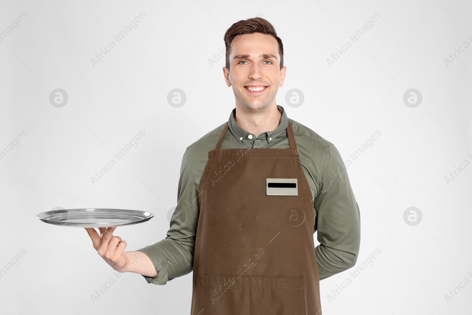 Photo of Handsome waiter with empty tray on light background