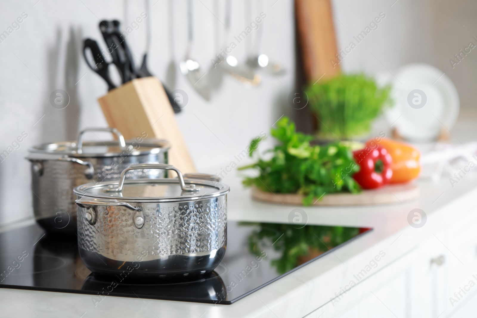 Photo of Pots with lids on cooktop in kitchen, space for text. Cooking utensils