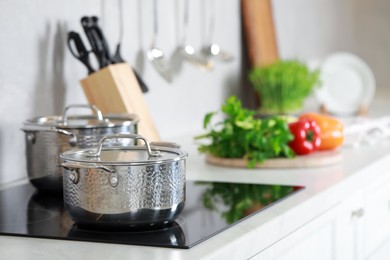 Pots with lids on cooktop in kitchen, space for text. Cooking utensils