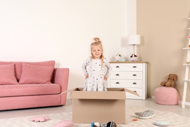 Cute little girl playing with cardboard box at home