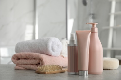 Photo of Different hair care products, towels and brush on table in bathroom