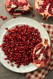 Photo of Tasty ripe pomegranate and grains on grey table, flat lay