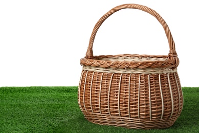 Empty wicker basket on green lawn against white background. Space for design. Easter item