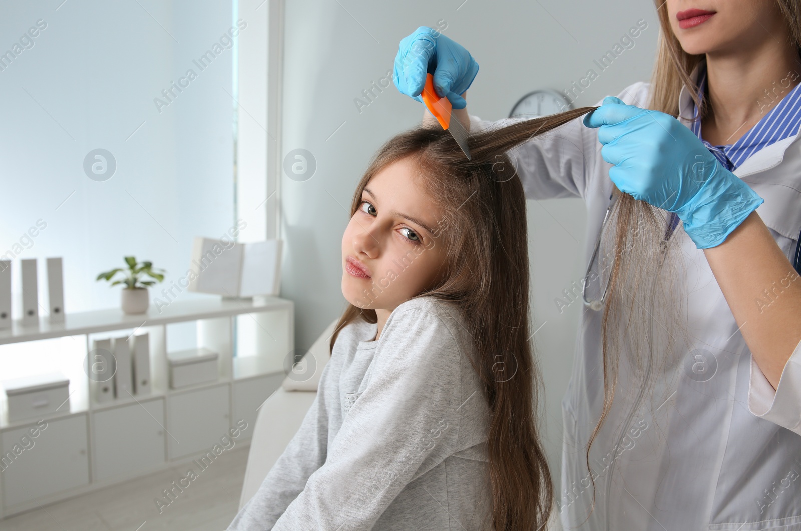 Photo of Doctor using nit comb on girl's hair in clinic. Anti lice treatment