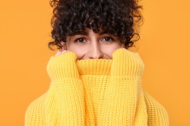 Young woman in stylish warm sweater on yellow background