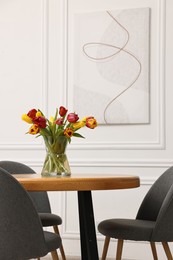 Photo of Vase with beautiful tulips on table in dining room