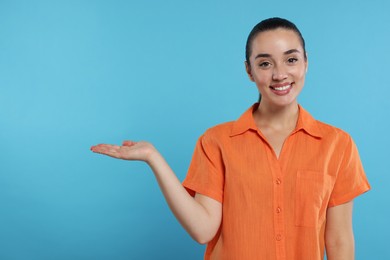 Photo of Special promotion. Smiling woman holding something on light blue background. Space for text