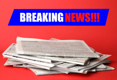 Image of Phrase Breaking News and stack of newspapers on red background. Journalist's work