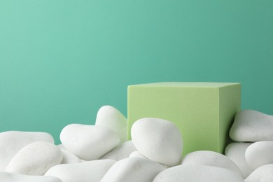 Photo of Presentation for product. Light green cube podium and white pebbles on color background. Space for text