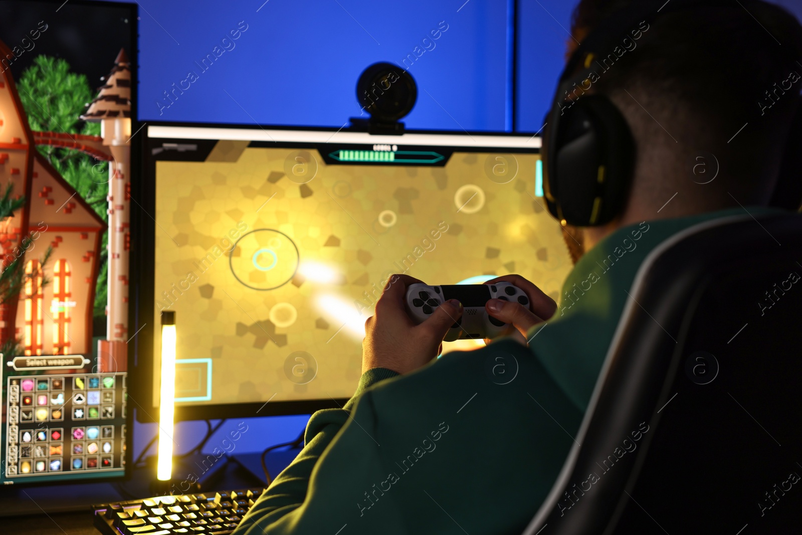 Photo of Man playing video games with controller at table indoors