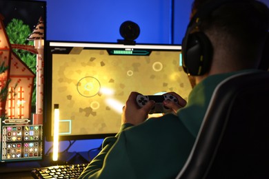 Photo of Man playing video games with controller at table indoors