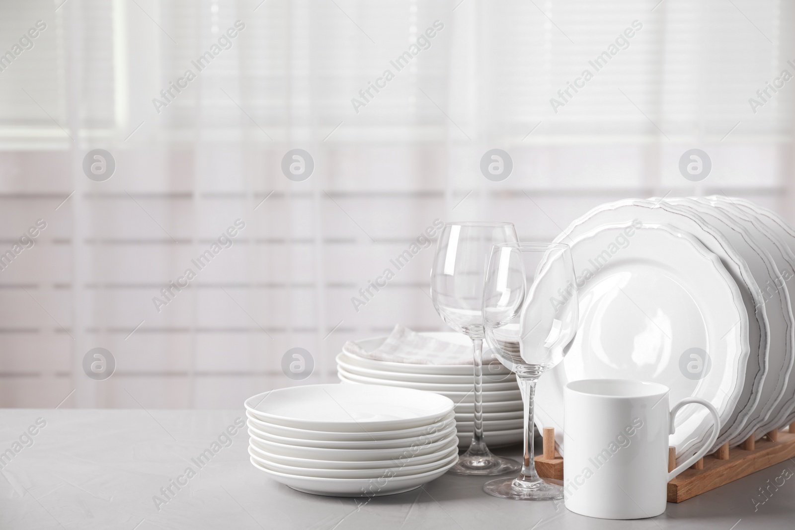 Photo of Set of clean tableware on light grey table. Space for text