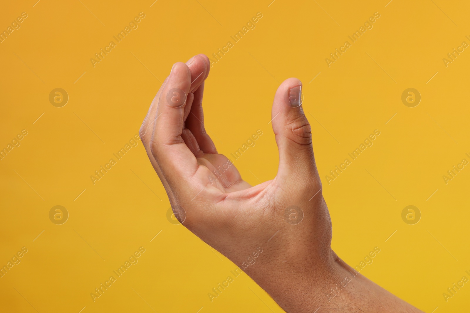 Photo of Man holding something in hand on orange background, closeup