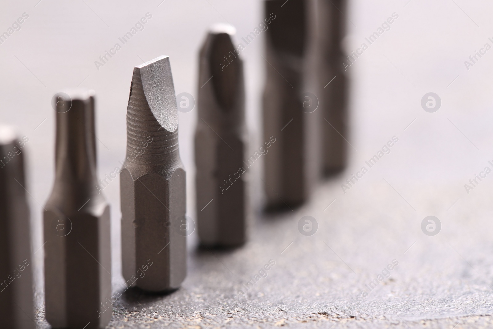 Photo of Different screwdriver bits on grey table, closeup