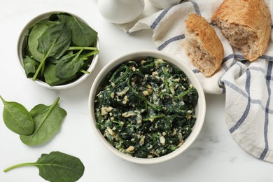 Photo of Tasty spinach dip with eggs in bowl and bread on white table, flat lay