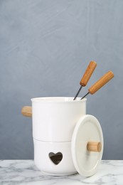 Photo of Fondue set on white marble table against light grey background