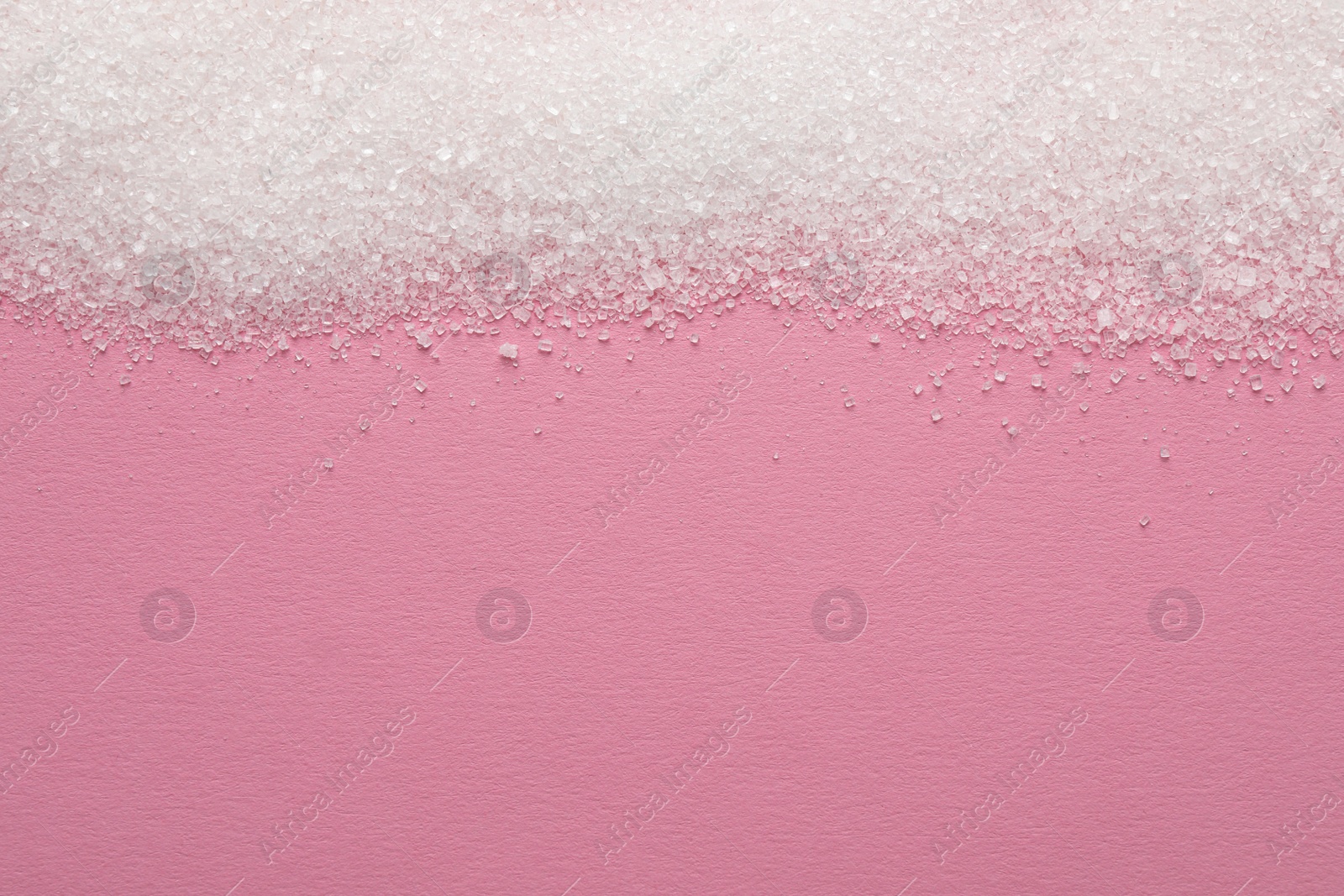 Photo of Granulated sugar on pink background, top view. Space for text