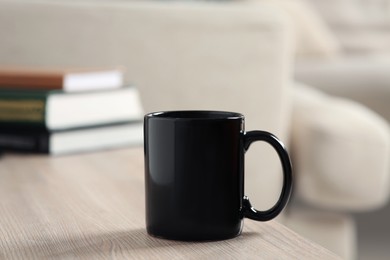 Black mug on wooden table indoors. Mockup for design