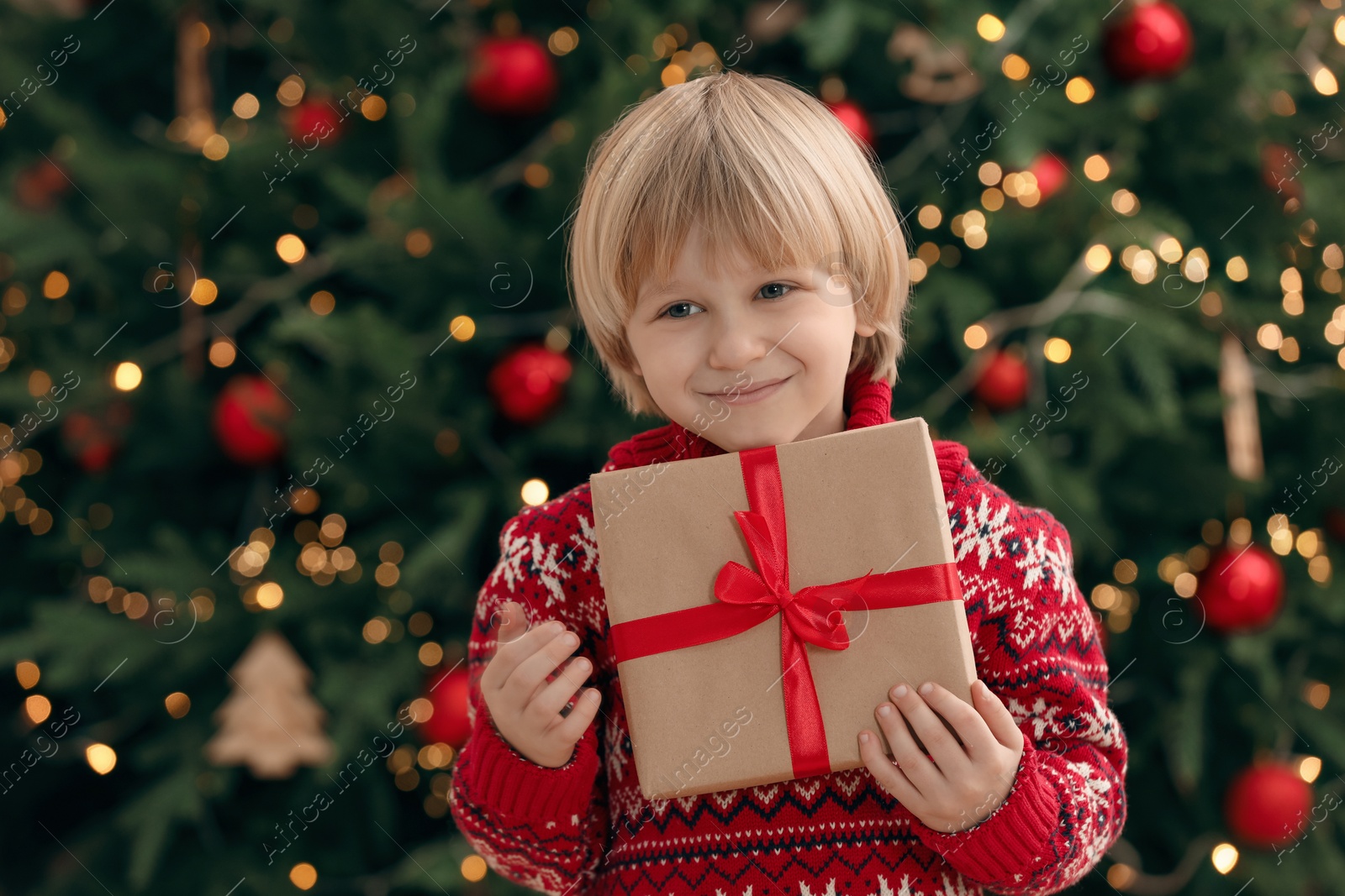 Photo of Little child with gift box near Christmas at home