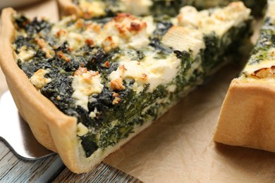 Photo of Taking piece of delicious homemade spinach quiche on table, closeup