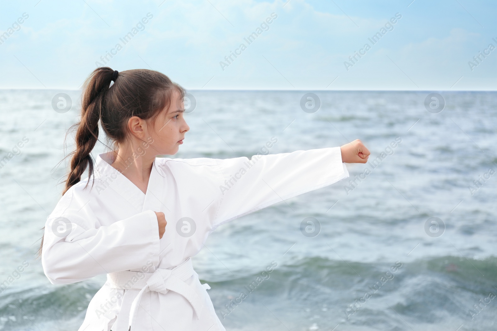 Photo of Cute little girl in kimono practicing karate near river