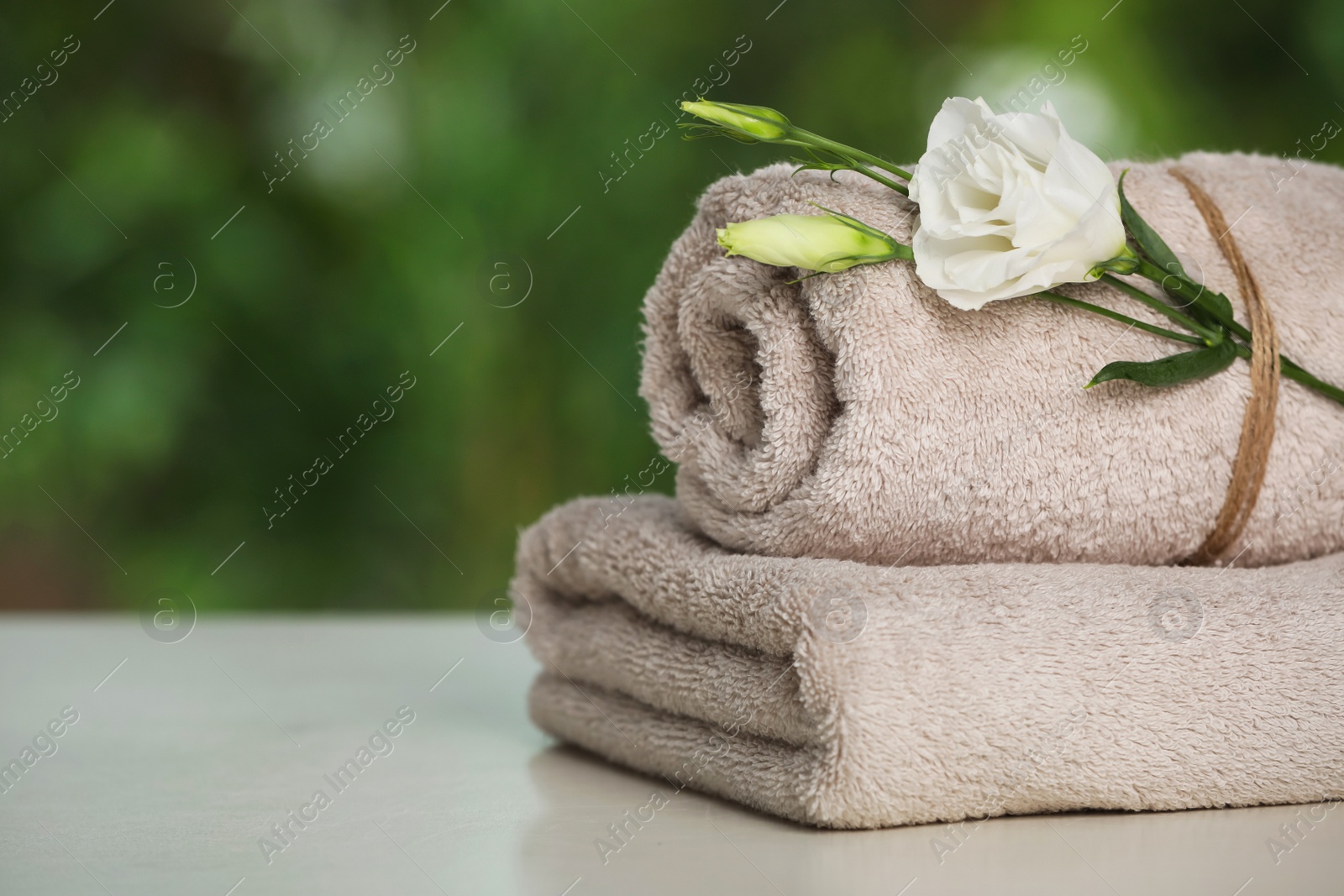 Photo of Beige soft towels on white table outdoors, closeup. Space for text