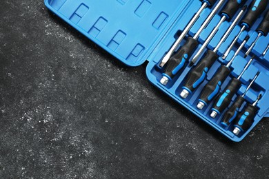 Photo of Set of screwdrivers in open toolbox on dark textured table, top view. Space for text