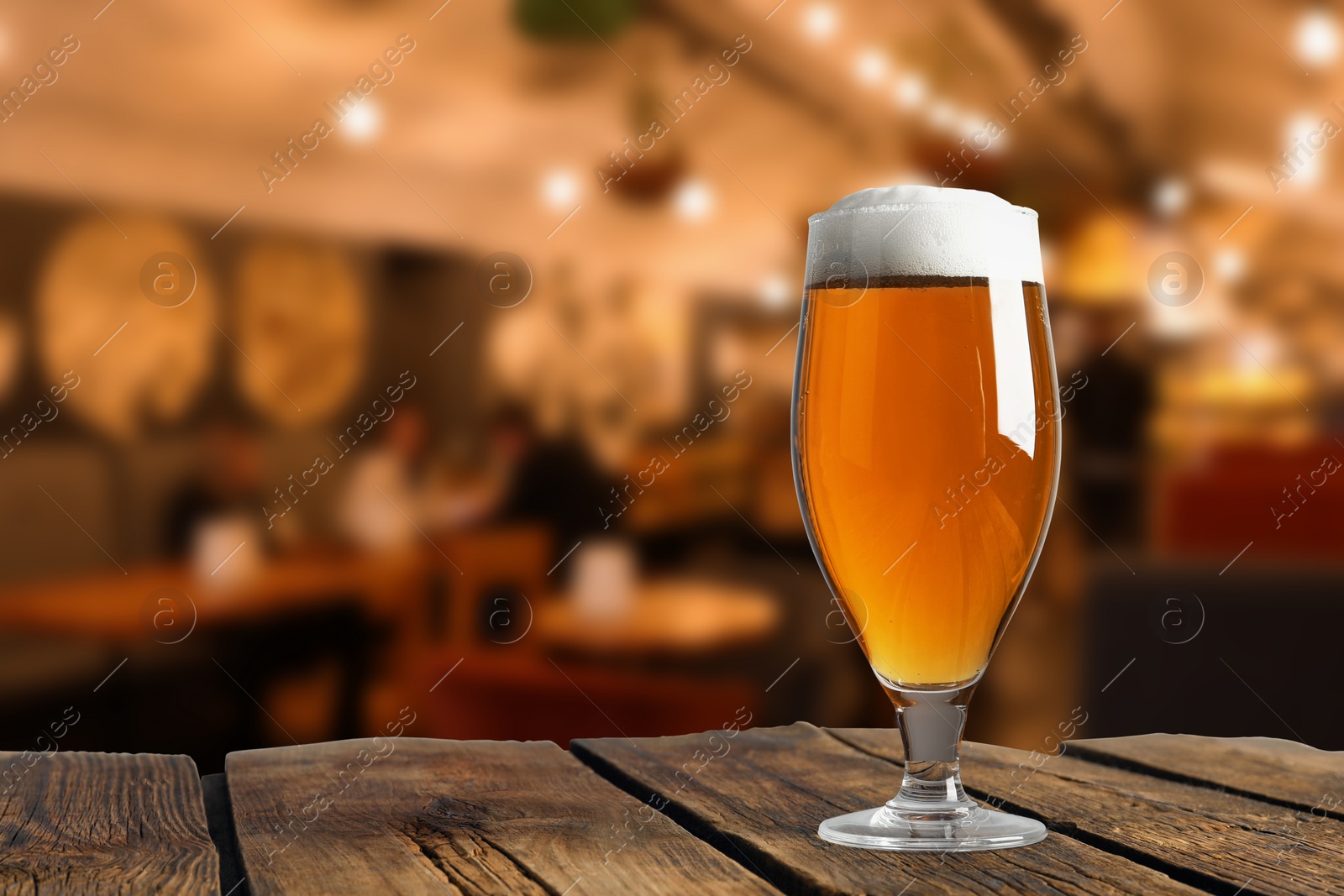 Image of Glass with fresh beer on wooden table in pub, space for text