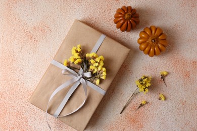 Photo of Pumpkin shaped candles and book decorated with flowers on beige textured background, flat lay