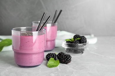 Photo of Delicious blackberry smoothie in glasses on marble table. Space for text