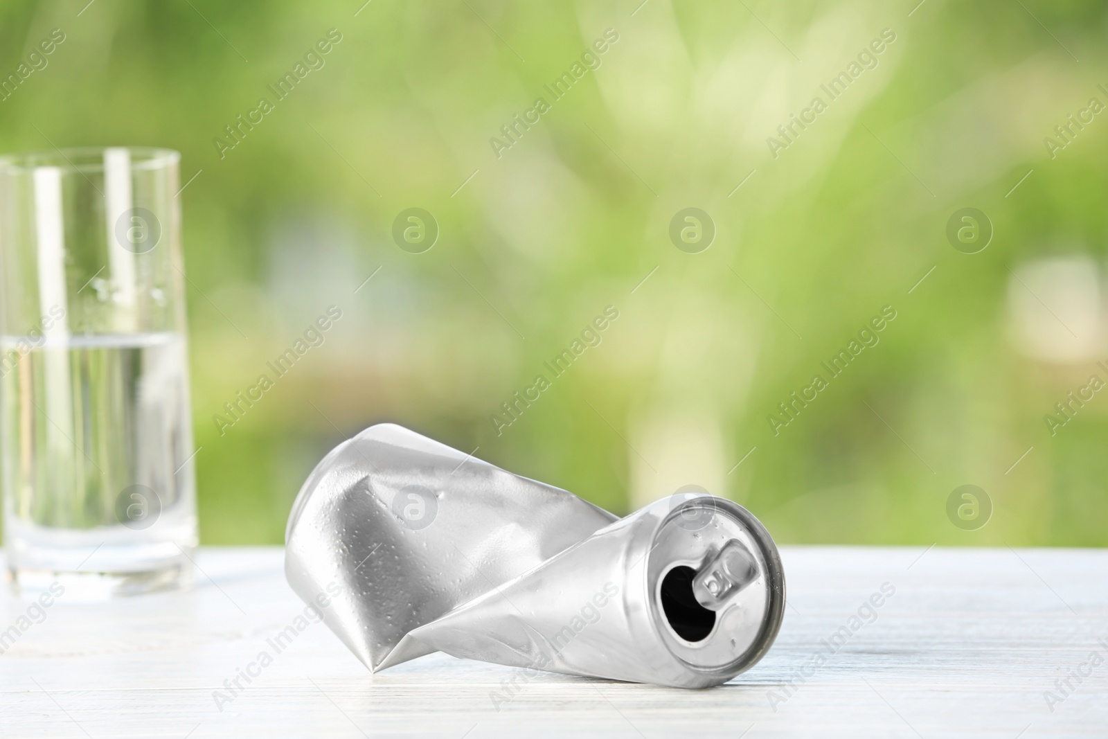 Photo of Crumpled aluminum can on table against blurred background. Metal waste recycling