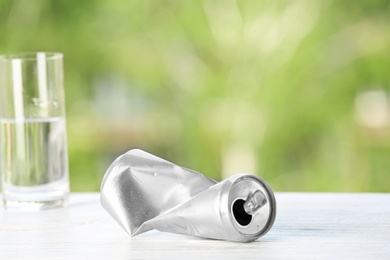 Crumpled aluminum can on table against blurred background. Metal waste recycling