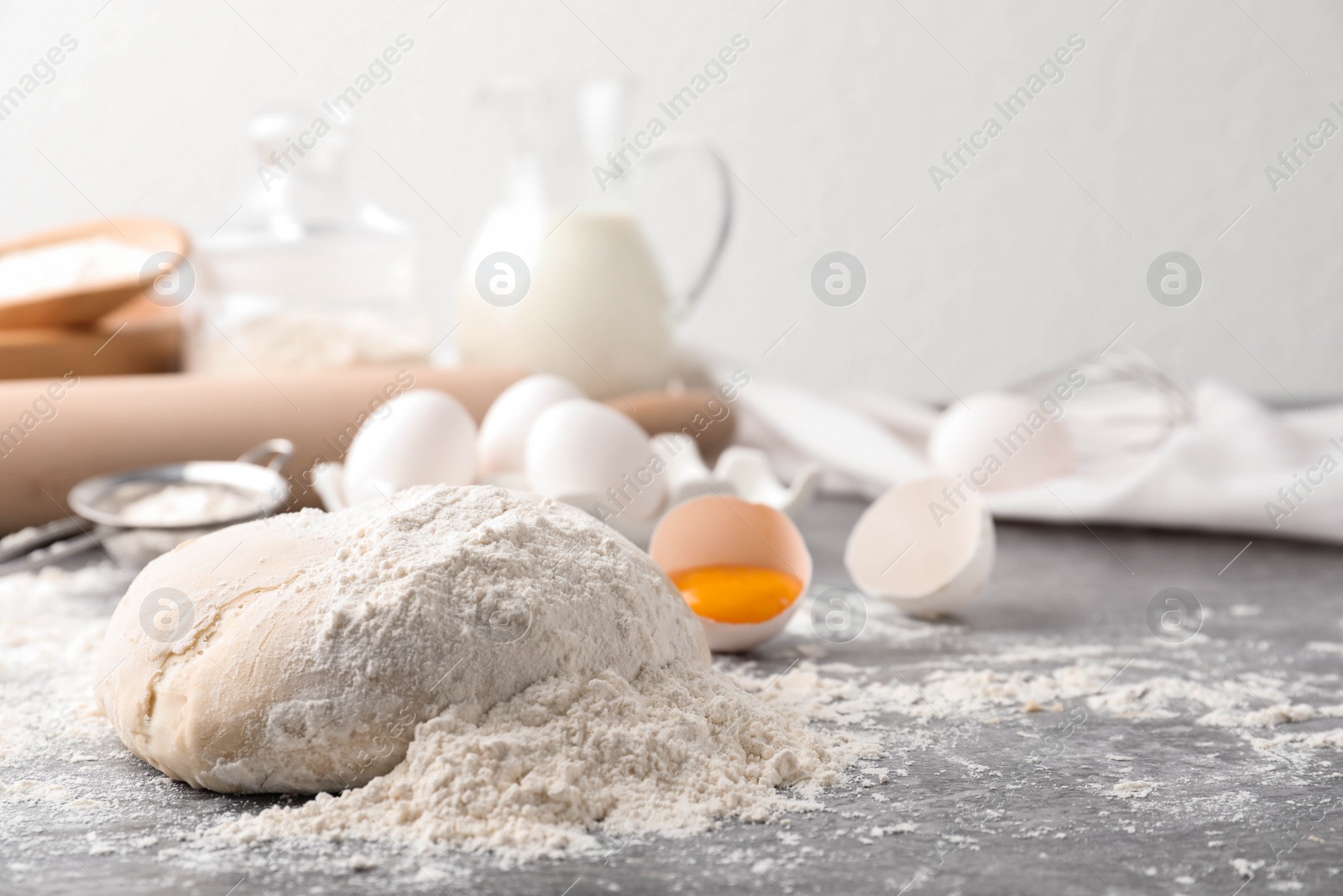 Photo of Wheat dough and products on grey table, space for text. Cooking pastries