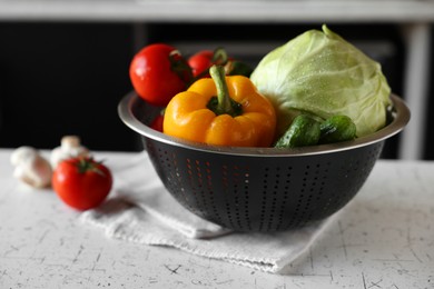 Photo of Metal colander with different wet vegetables on white textured table