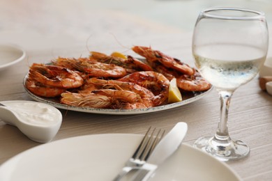 Photo of Plate of delicious cooked shrimps served with lemon and wine at table, closeup