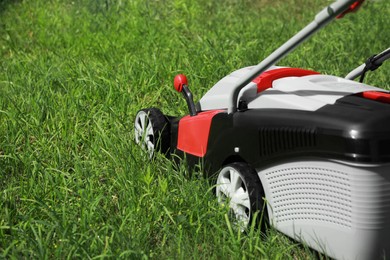 Lawn mower on green grass in garden, space for text