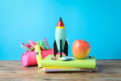 Bright toy rocket and school supplies on wooden table