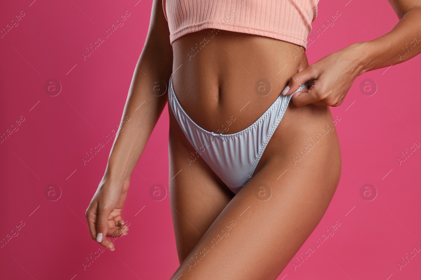 Photo of Woman in white sexy panties and top on pink background, closeup