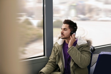 Photo of Young man listening to music with headphones in public transport