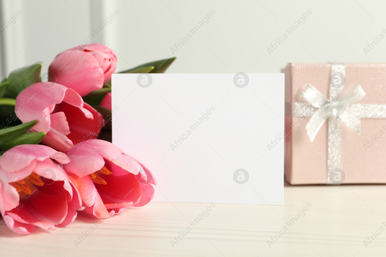 Photo of Happy Mother's Day. Beautiful tulips, gift box and blank card on white wooden table, closeup