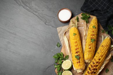 Photo of Tasty grilled corn on black table, flat lay. Space for text