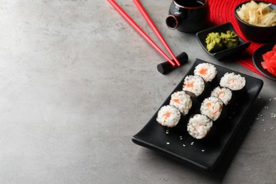 Photo of Tasty sushi rolls served on grey table. Space for text