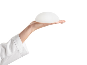 Photo of Doctor holding silicone implant for breast augmentation on white background. Cosmetic surgery