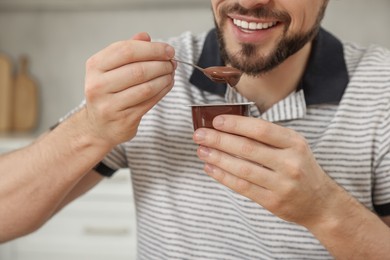 Man with tasty yogurt in kitchen, closeup
