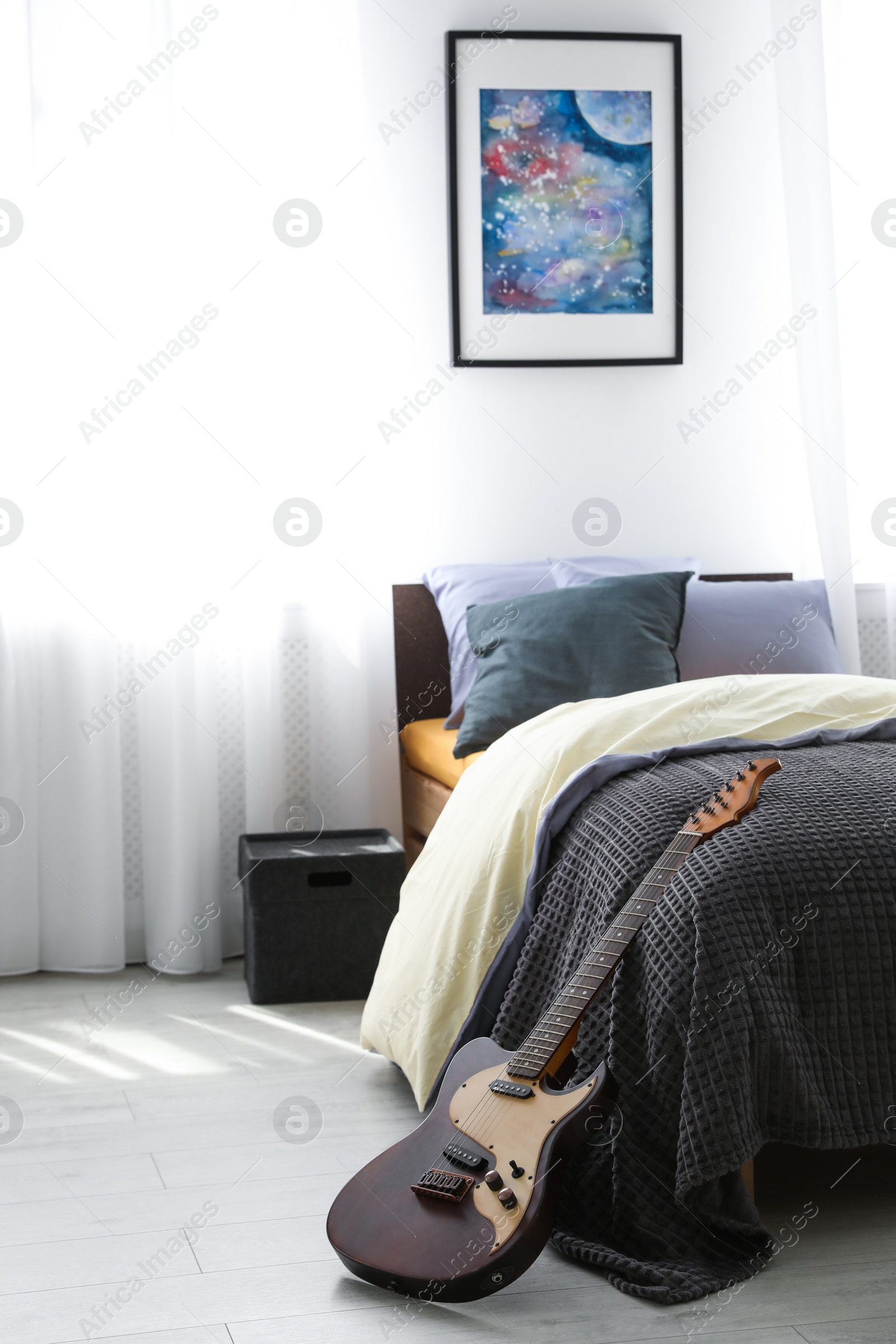Photo of Electric guitar near bed in modern teenager's room interior