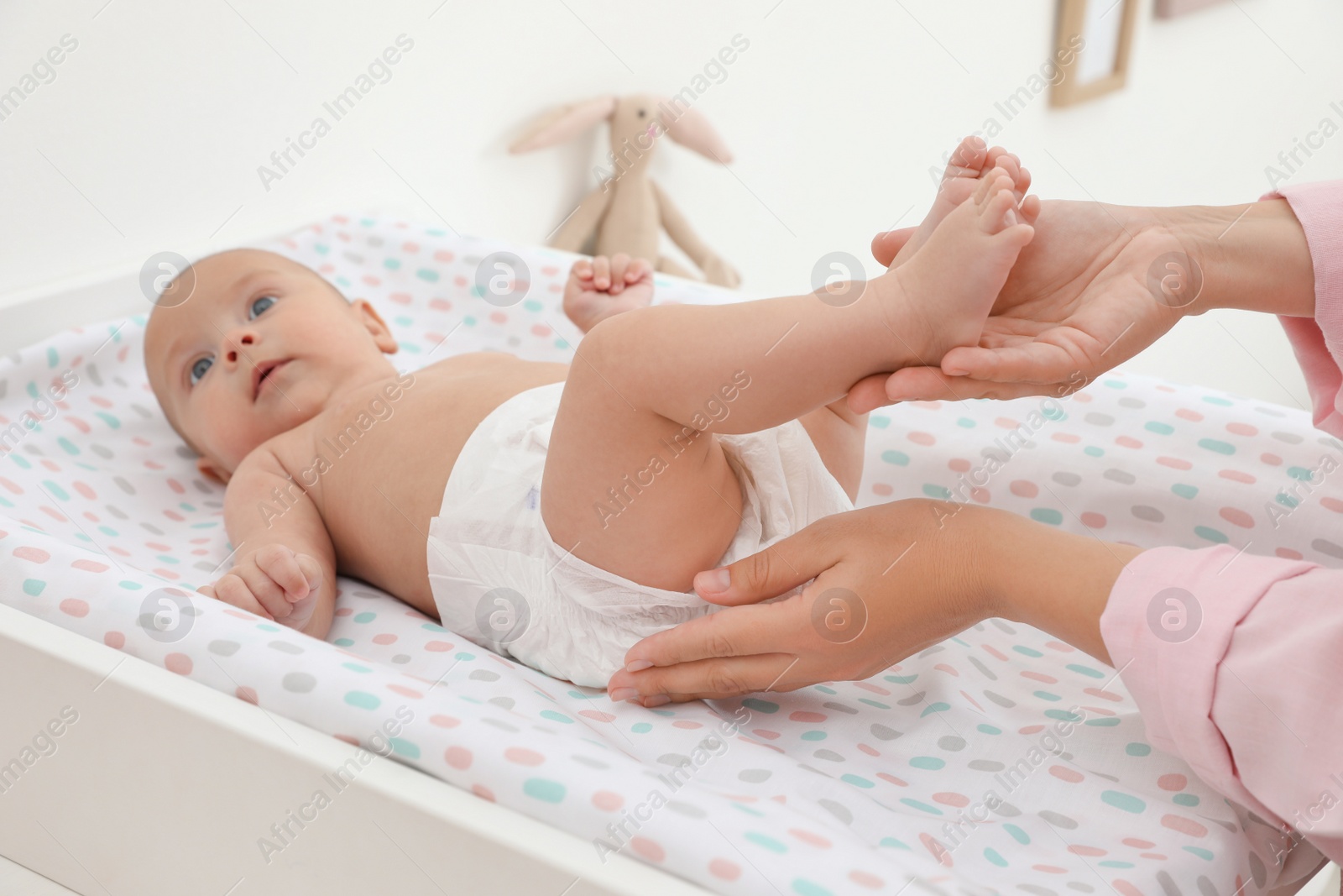 Photo of Mother changing her baby's diaper on table at home