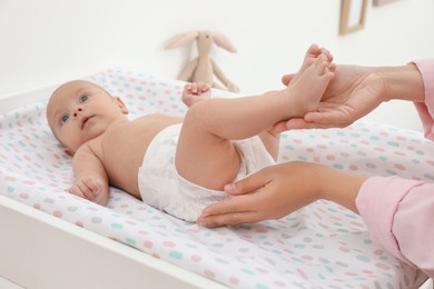 Mother changing her baby's diaper on table at home