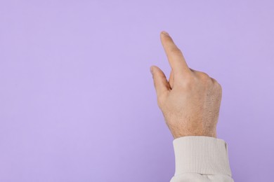 Photo of Man holding something on violet background, closeup of hand. Space for text